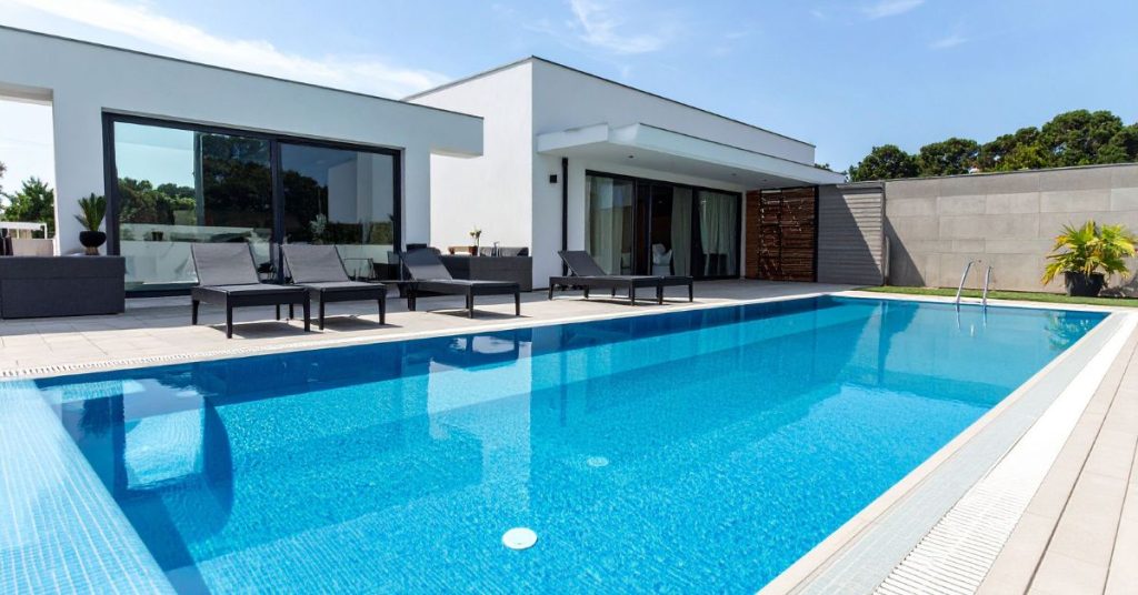 Contemporary in-ground swimming pool with modern outdoor lounge seating