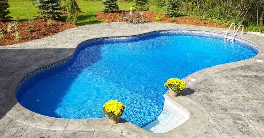 Freeform residential swimming pool with decorative stamped concrete deck